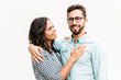 © Mangostar - Positive united family couple hugging, talking and posing for camera. Young woman in casual and man in glasses standing isolated over white background. Relationship and bonding concept