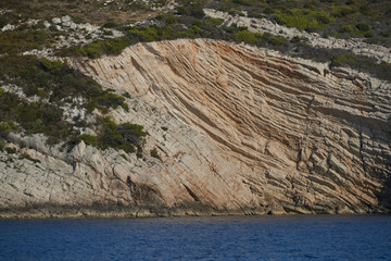 Beautiful high cliff with caves and hanging rocks of a mountain in Adriatic sea, a crevice, colorful