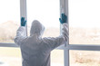 © F8  \ Suport Ukraine - Man at home in quarantine with mask looks out of the closed window to protect himself from the pandemic of n-cov19 Coronavirus