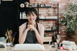 © PR Image Factory - Portrait of happy professional nail master sitting at working place in salon. young beautiful asian japanese lady manicurist worker in nail workshop. beautician in apron face camera smiling in studio
