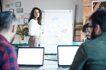 Wall Mural - Business trainer presenting flowchart on board to audience. Business colleagues in casual working together in contemporary office space. Corporate training concept