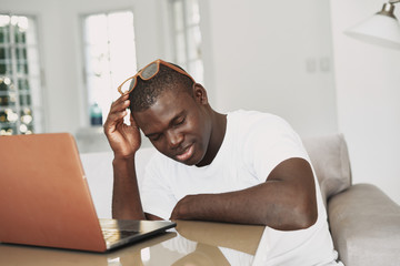 Wall Mural - A man of African appearance at home in front of a laptop