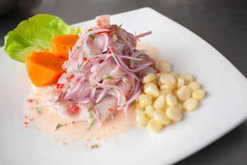 Wall Mural - Peruvian seafood: fish cebiche with onion, chili, sweet corn and sweet potato served on a white plate