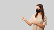 © South House Studio - brunette woman in mask pointing to copy space isolated over white bg