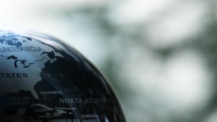 Wall Mural - Macro of a spinning Earth globe with a forest background in slow motion