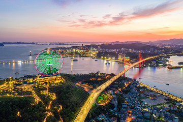 Wall Mural - Panorama of Ha Long City, Vietnam, with Bai Chay bridge. Near Halong Bay, UNESCO World Heritage Site. Popular landmark, famous destination of Vietnam. View from center city to Ha Long bay.