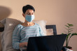 © Володимир Захаров - Woman working from home wearing protective mask. Girl with short black hair sitting in bed with laptop remotely working during coronavirus pandemic. Distance working on self-isolation or quarantine.