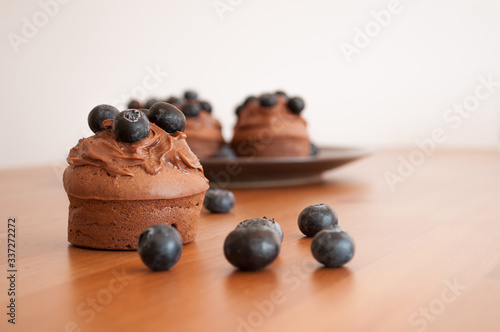 Fotografía Czekoladowe muffiny z jagodami na drewnianym stole.