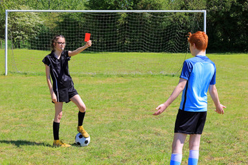 A young girl football referee sending off a young boy during a game of soccer.