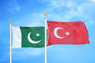 Pakistan and Turkey two flags on flagpoles and blue cloudy sky