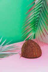 Wall Mural - Coconut shell and palm leaf on pink and turquoise background. Hot summer vacation concept. Tropical style. Isometric corner.