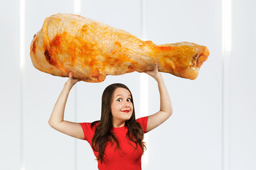 Young hunger pretty funny girl holds huge and large chicken big leg and laugh