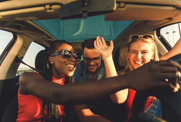 Wall Mural - Three best friends enjoying at road trip traveling at vacation in the car.