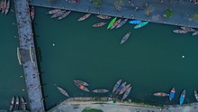 Aerial Top Down View Of Colourful Long Tail Boats Moored To Embankment On Thu Bon River Near Bridge, Hoi An Ancient Town, Quang Nam Province, Vietnam. Popular Travel Destination.