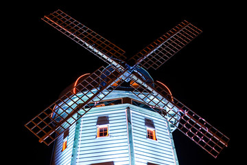 Big, iconic mill lightet with moderln led lights in restaurant park.