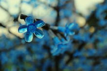 Blue Artificial Flower On A Tree Branch On A Background Of Blue Flowers