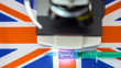 The UK flag with the microscope and the syringe for coronavirus vaccine COVID-19