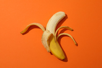 Wall Mural - Opened banana on orange background. Fresh fruit