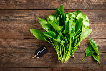 Wall Mural - Fresh bundle of spinach on rustic wooden background