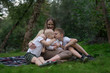 © somemeans - Young mom with three little children having picnic in summer. Big cousin hug and kiss her younger sister.