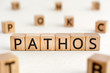 Pathos - word from wooden blocks with letters, a quality causes feelings of sadness or sympathy pathos concept, random letters around white background