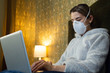© Igor - patient in protective mask against coronavirus works at a laptop in bed. beautiful girl works at home in bed at a laptop. beautiful girl works at home during quarantine. Covid-19. Covid-20. freelance.