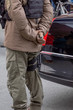 © Dolores  Harvey - A male police officer stands or is straddled between a white thick line in the middle of a road. The officer has a gun strapped to its leg at the thigh.The cop is wearing weather-proof tactical pants.