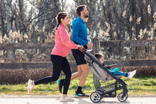 Sporty Young Couple With Her Little Son Running While Enjoying The Time Together Outdoor.