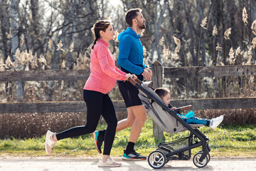 Sporty young couple with her little son running while enjoying the time together outdoor.