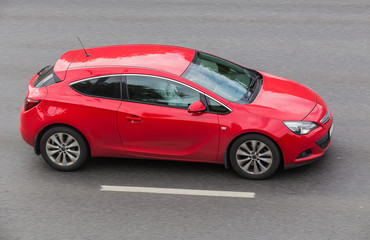 Poster - Red car moves on an asphalt road.