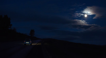 Wall Mural - car moves at night on a moonlit road