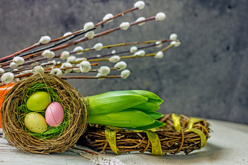 Beautiful Easter card with a decorative nest with Easter eggs and pussy-willow twigs on a wooden light background