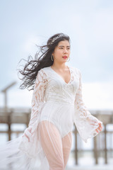 Beautiful woman in white dress happily strolling at the beach, beautiful woman dressed in white bride