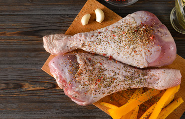 Turkey legs with spices and garlic, sweet pepper on the kitchen Board on a wooden , raw meat