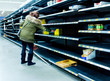 © F Armstrong Photo - Woman grabbing product of of thinly stocked shelves at a supermarket during the Coronavirus Pandemic