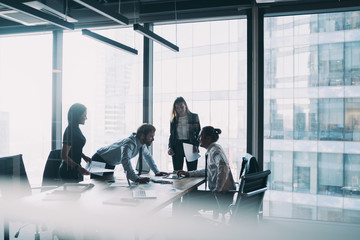 Wall Mural - Male and female professionals teamworking during brainstorming cooperation on paper documents, group of diverse employers discussing corporate investment of firm capital briefing in conference room