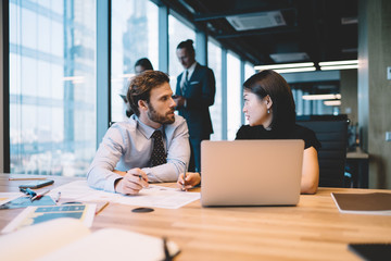 Wall Mural - Diverse male and female financial experts discussing information during accounting process at desktop with modern laptop computer, intelligent colleagues consultancy about report of startup project