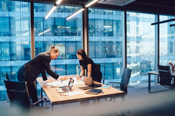 Wall Mural - Smart caucasian male and female colleagues in formal wear planning project organization together share ideas on meeting, intelligent business partners checking sketches cooperating in office