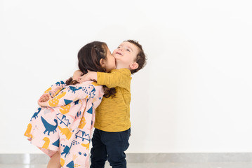 Portrait happy brother and sister huging. Kissing little boy and girl. Siblings day.