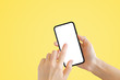 © Angkana - Business Communication Concept : Hand holding old black smartphone with Yellow background.