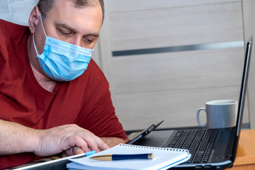 Wall Mural - quarantine due coronavirus pandemic. stay at home. business man working from home, wear a protective mask. Work from home with disinfectant gel. remote work, learning due to the epidemic COVID-19.