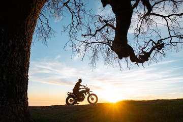 Biker riding motorcycle on landscape against cloudy sky