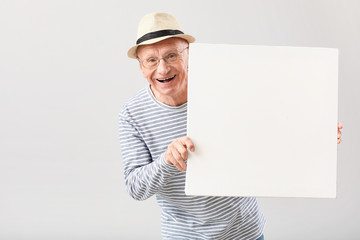 Poster - Portrait of elderly man with blank poster on grey background