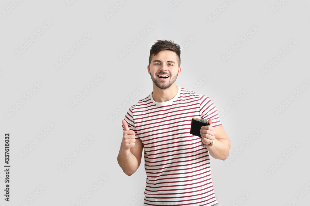 Happy man with purse on light background