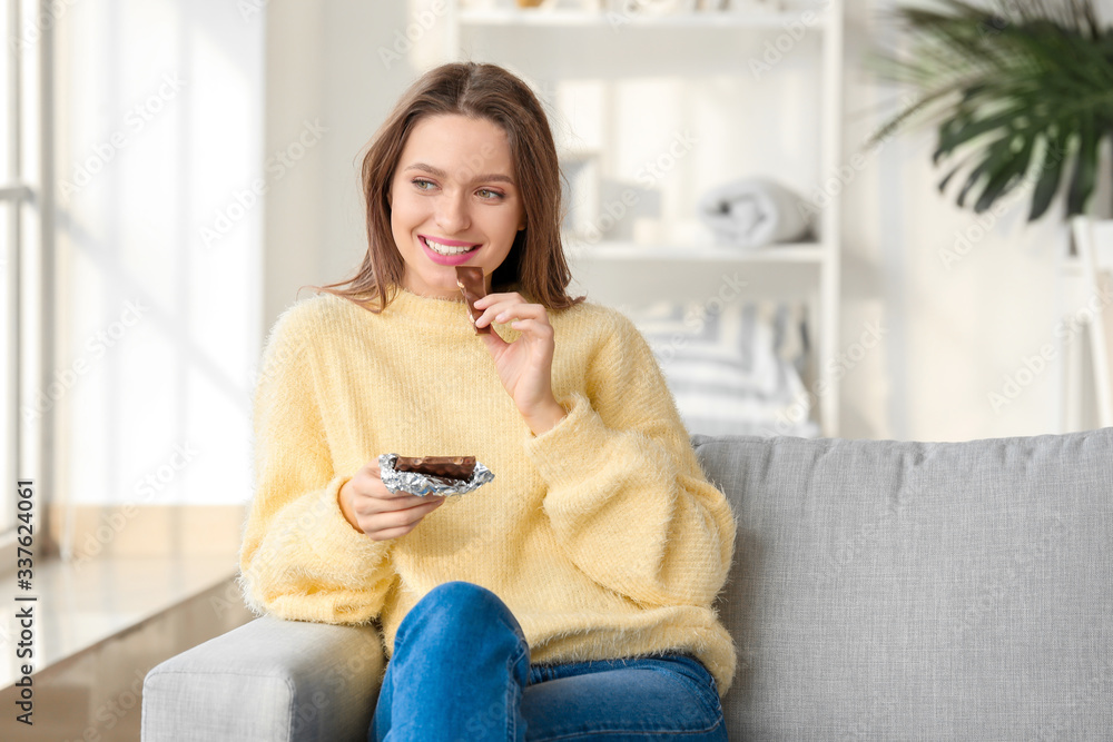 Beautiful young woman eating chocolate at home