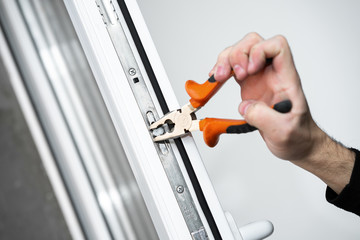 Professional master for repair and installation of windows, sets up a window opening system in winter mode