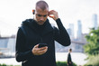 © BullRun - Pensive sportsman walking in park choosing music on phone for training