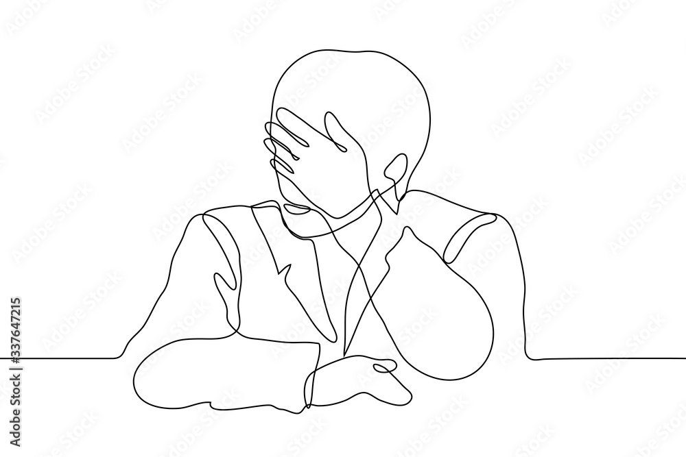 A man in a jacket (torso) sits at a table and put his hand to his face ...