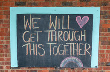 Chalk Sign Saying We Will Get Through This Together On A Brick Wall.  Written During The Coronavirus Pandemic Lockdown.