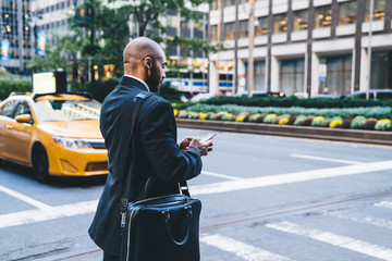 Wall Mural - Black worker typing message while crossing road